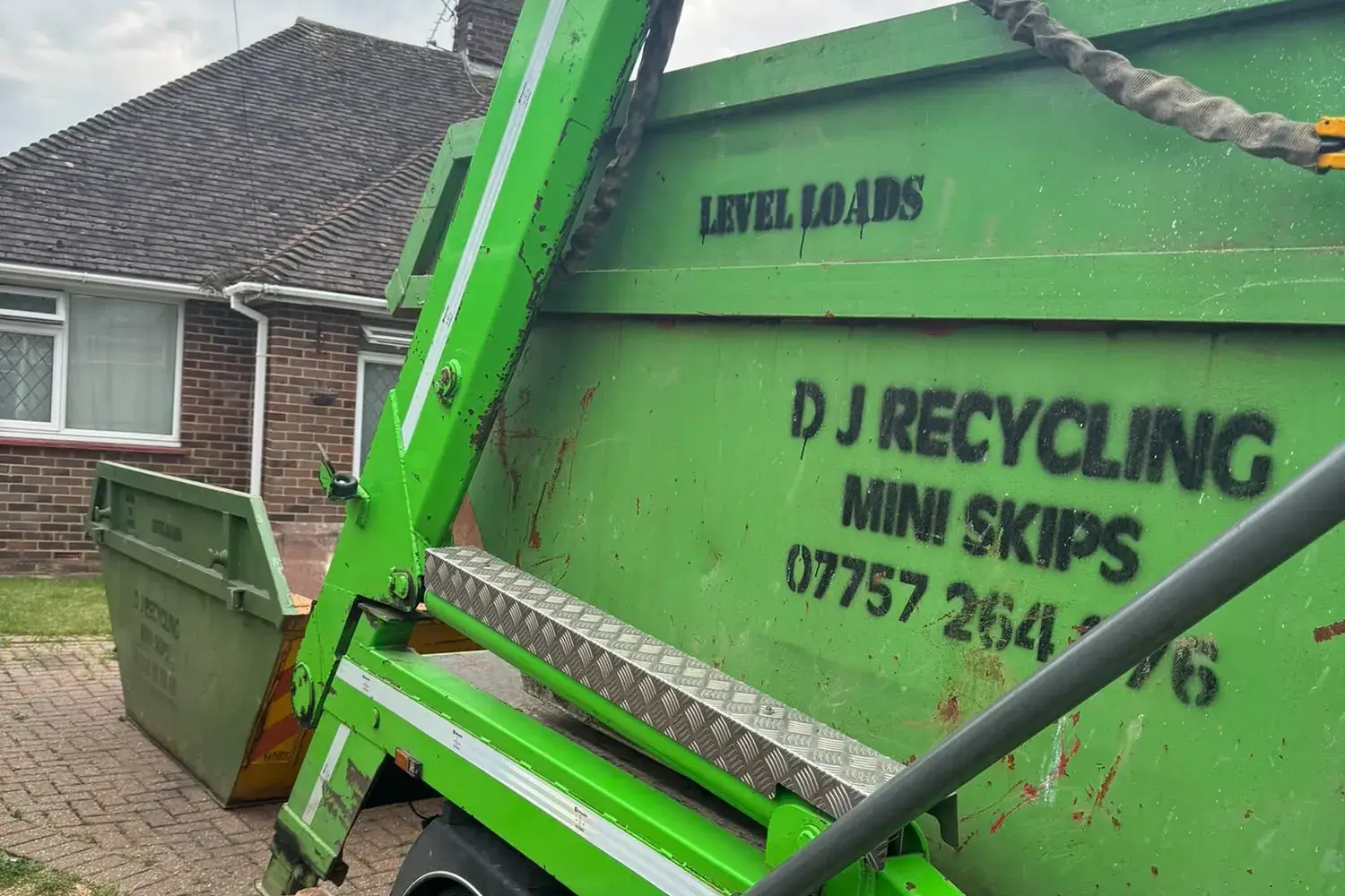 DJ Recycling lowering a mini skip onto a bungalow driveway