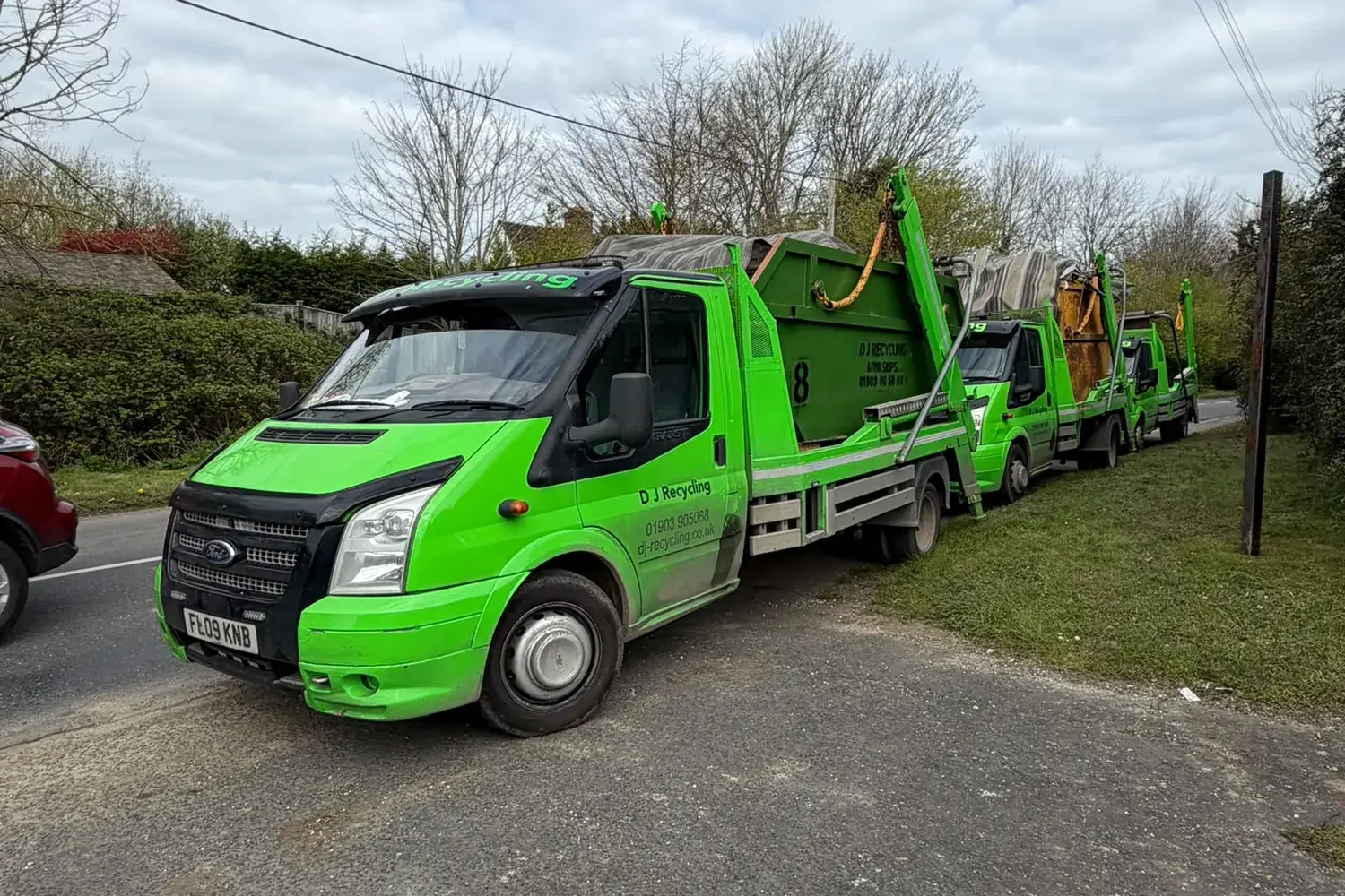 Three DJ Recycling skip lorries parked on a West Sussex road